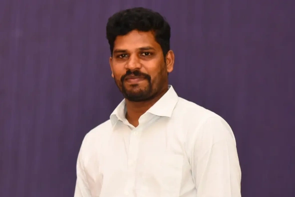 Anandakumar posing for camera behind the purple screen