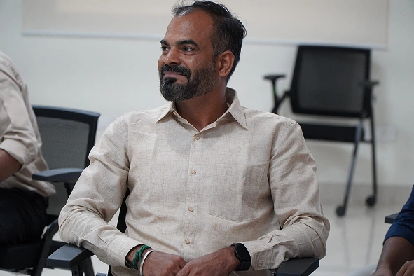 Saravanan Ganesan in office seating in a chair